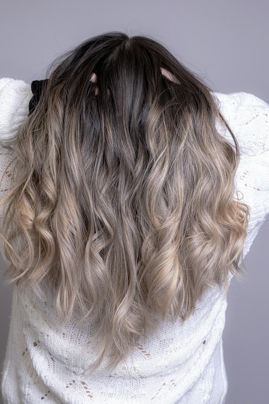 Long wavy hair with a dark root melting into cool ash blonde ends
